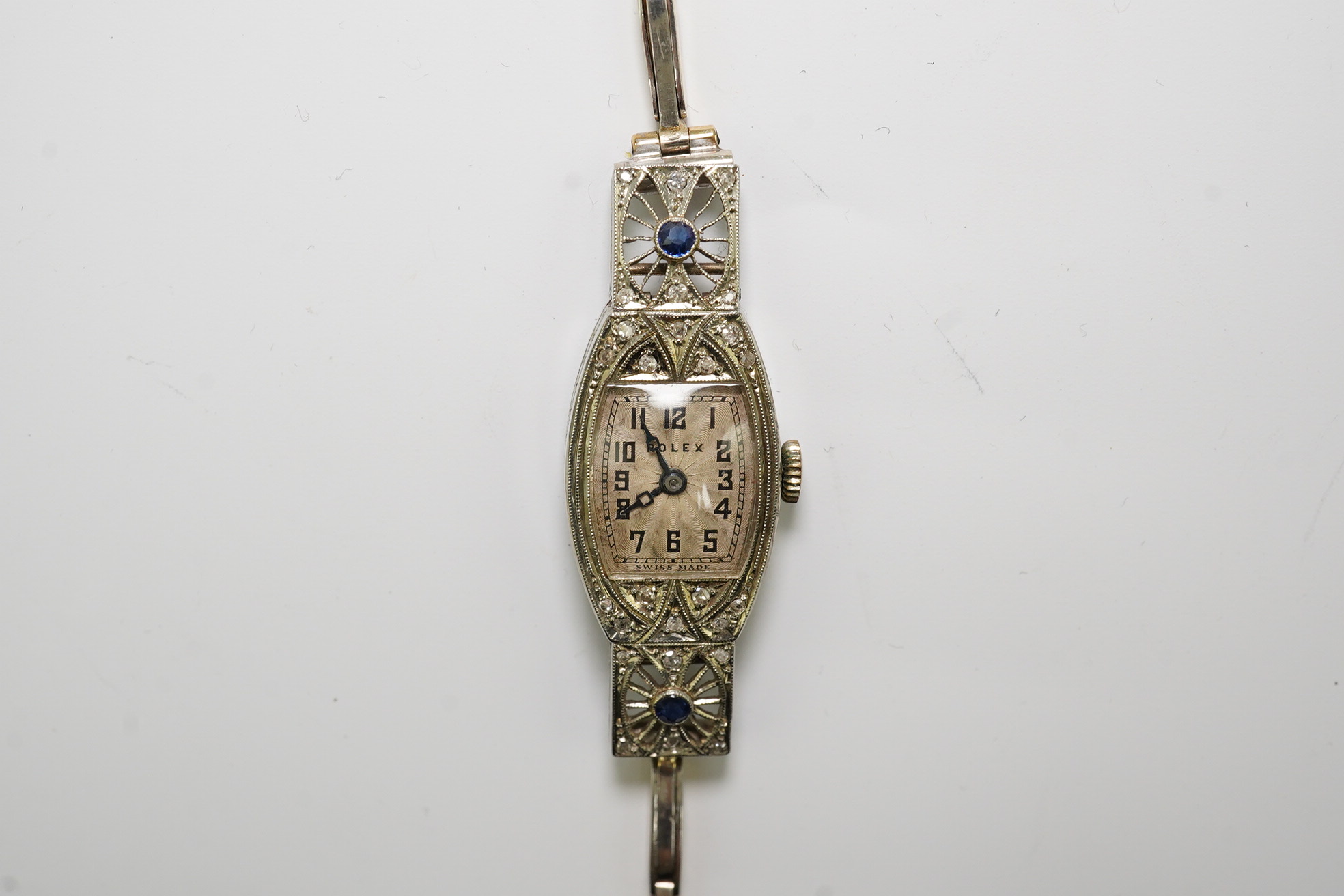 A lady's 1930's Art Deco pierced 18ct gold, sapphire and diamond set Rolex manual wind cocktail watch, on an 18ct gold and platinum expanding bracelet